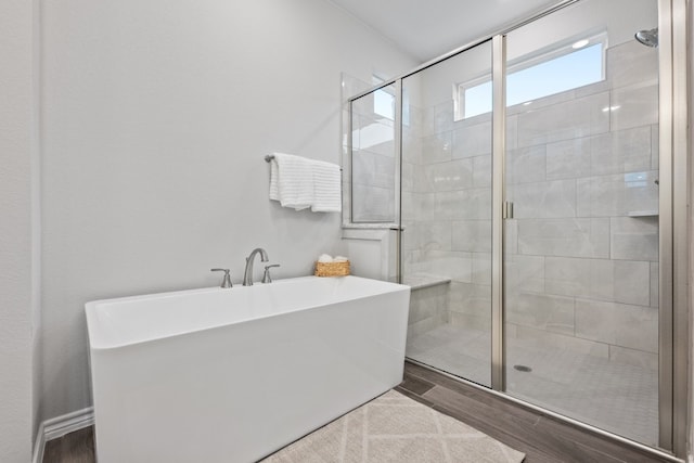 full bath with a stall shower, a freestanding tub, and wood finished floors