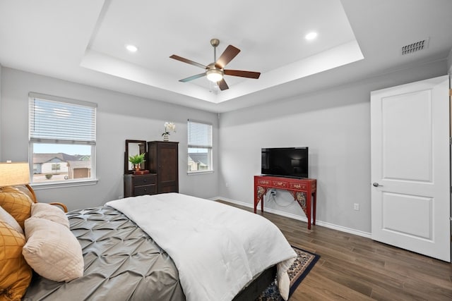 bedroom with dark hardwood / wood-style floors, a raised ceiling, and ceiling fan