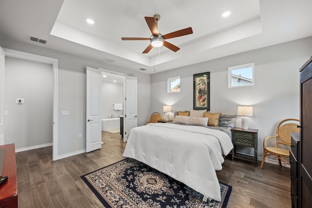 bedroom with a tray ceiling, dark wood-type flooring, and visible vents