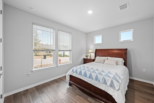 bedroom with baseboards, visible vents, and wood finished floors