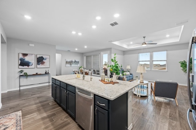 kitchen featuring sink, dark hardwood / wood-style flooring, stainless steel dishwasher, a raised ceiling, and a center island with sink