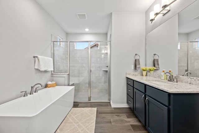 bathroom with visible vents, a soaking tub, wood finished floors, vanity, and a shower stall