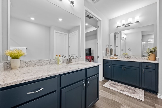 full bath with wood finished floors, two vanities, a sink, and recessed lighting