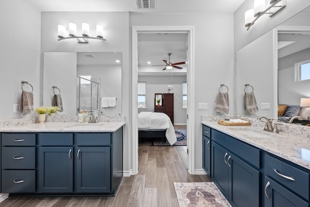 bathroom with hardwood / wood-style flooring, vanity, a shower with door, and ceiling fan