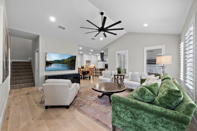 living room featuring vaulted ceiling, ceiling fan, and light hardwood / wood-style flooring