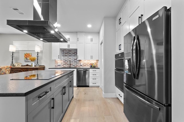 kitchen with light hardwood / wood-style flooring, island range hood, white cabinets, and black appliances