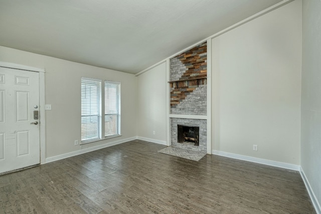 unfurnished living room with dark hardwood / wood-style flooring, a stone fireplace, and lofted ceiling