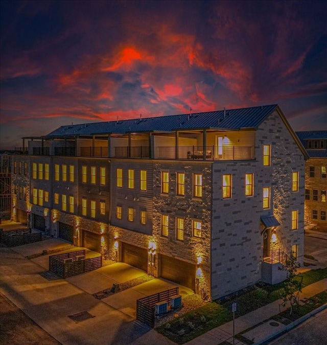 back house at dusk with a balcony and a garage