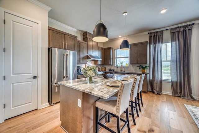 kitchen with high quality fridge, ornamental molding, decorative light fixtures, and a center island