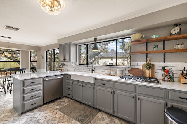 kitchen featuring pendant lighting, crown molding, appliances with stainless steel finishes, tasteful backsplash, and kitchen peninsula