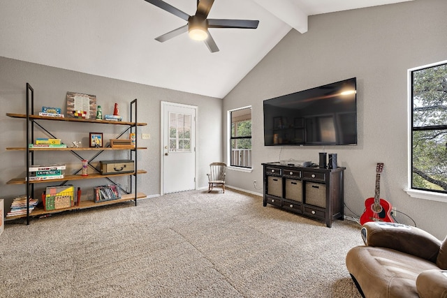 living area featuring ceiling fan, a healthy amount of sunlight, carpet, and vaulted ceiling with beams