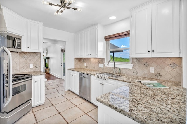 kitchen featuring stainless steel appliances, light stone countertops, sink, and white cabinets