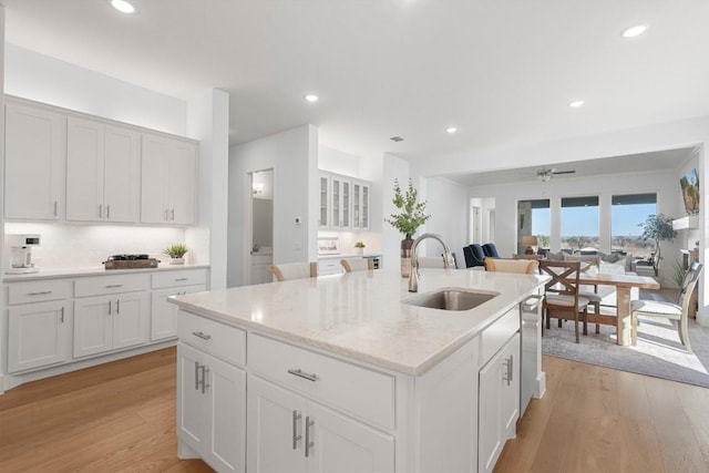 kitchen featuring white cabinetry, a kitchen island with sink, sink, and light hardwood / wood-style flooring