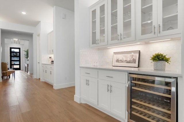 bar featuring wine cooler, light hardwood / wood-style floors, tasteful backsplash, and white cabinets