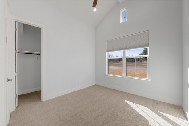 unfurnished bedroom featuring a closet, high vaulted ceiling, light carpet, and multiple windows