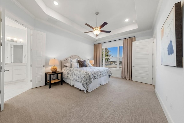 carpeted bedroom with ceiling fan, ensuite bathroom, and a tray ceiling