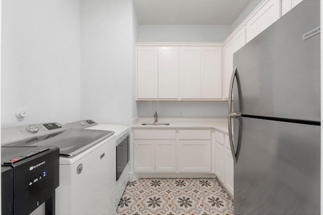 washroom featuring light tile patterned flooring, cabinets, separate washer and dryer, and sink