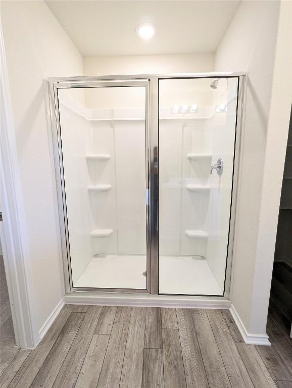 bathroom featuring wood-type flooring and a shower with shower door