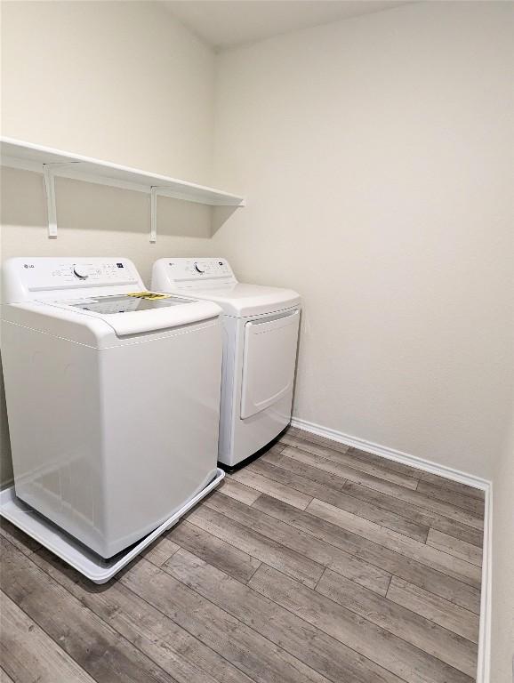 clothes washing area featuring washer and clothes dryer and light wood-type flooring