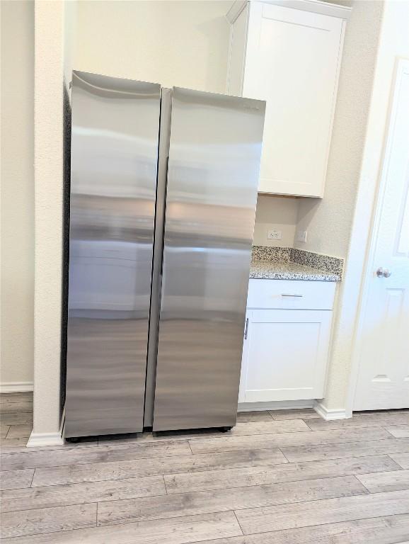 kitchen with white cabinets, stainless steel fridge, and light hardwood / wood-style floors