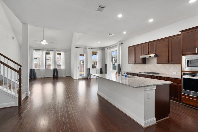 kitchen with an island with sink, sink, backsplash, dark hardwood / wood-style flooring, and stainless steel appliances