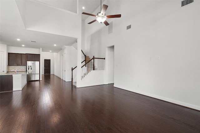 unfurnished living room with dark wood-type flooring, ceiling fan, sink, and a high ceiling