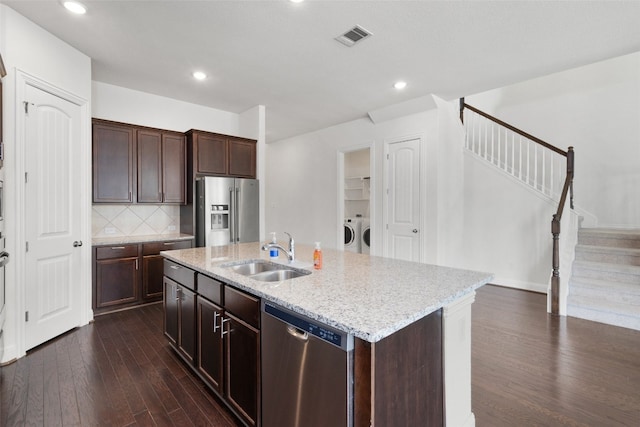 kitchen featuring washing machine and clothes dryer, sink, dark hardwood / wood-style floors, an island with sink, and stainless steel appliances