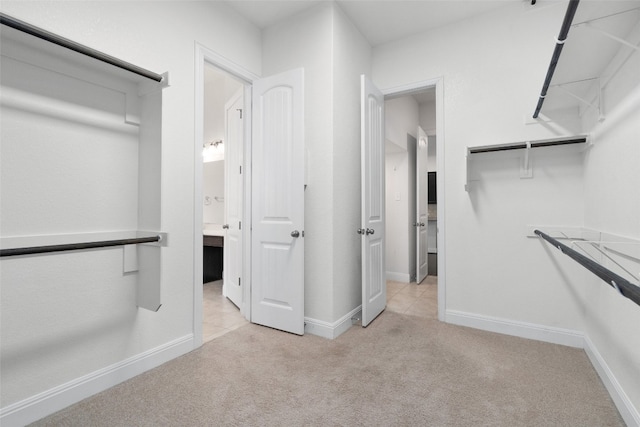 walk in closet with light colored carpet