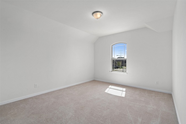 spare room with light colored carpet and vaulted ceiling