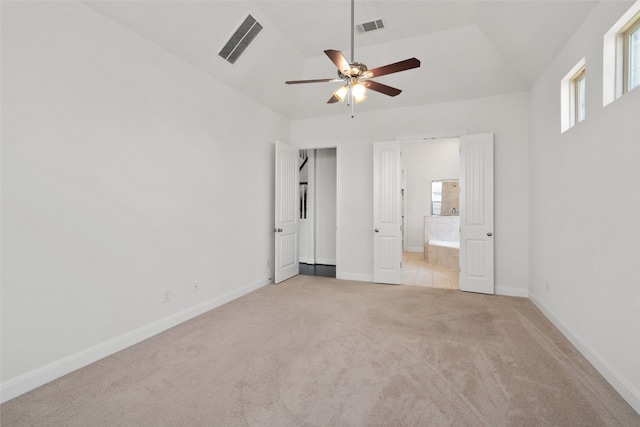 unfurnished bedroom featuring light carpet, connected bathroom, lofted ceiling, and ceiling fan