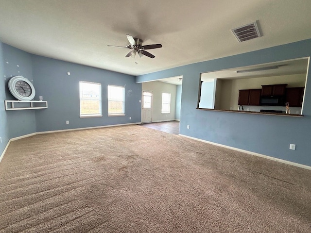 unfurnished living room featuring ceiling fan and carpet flooring