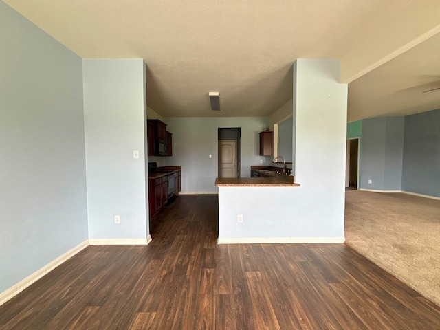 kitchen with dark wood-type flooring, kitchen peninsula, sink, and stove