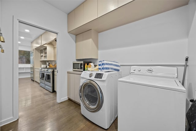 laundry area with cabinets, wood-type flooring, and separate washer and dryer