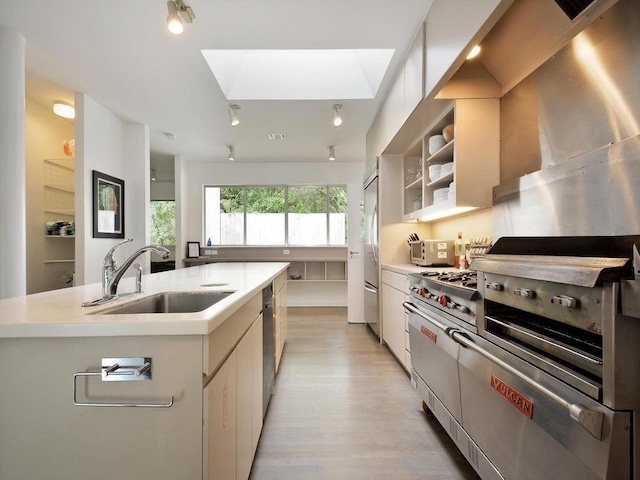 2909 Stratford Dr, Austin, TX 78746 - kitchen with high end appliances, light countertops, light wood-type flooring, a skylight, and white cabinets