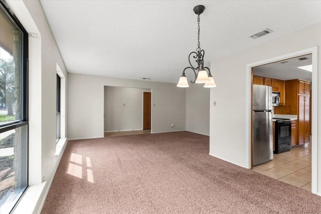 carpeted empty room with an inviting chandelier and a textured ceiling