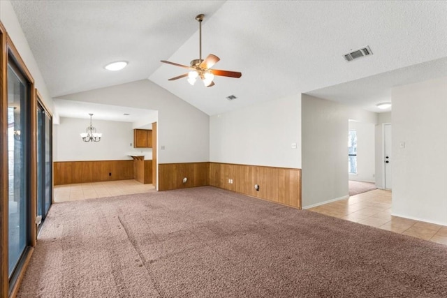 carpeted empty room featuring lofted ceiling, a textured ceiling, and wood walls