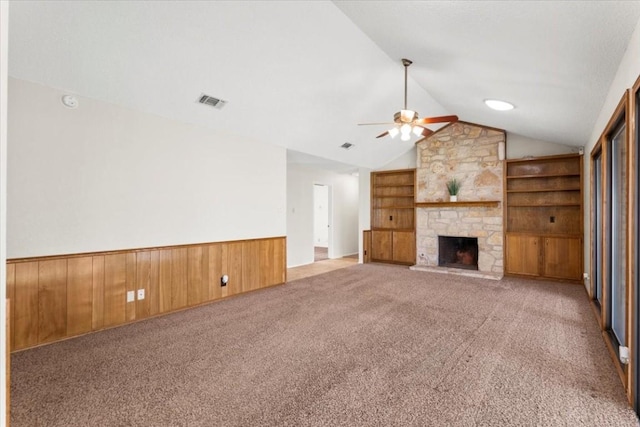 unfurnished living room with light colored carpet, lofted ceiling, a fireplace, and built in features