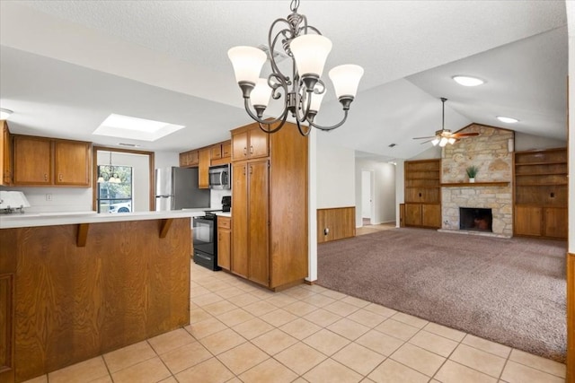 kitchen with appliances with stainless steel finishes, pendant lighting, a fireplace, a kitchen bar, and light carpet