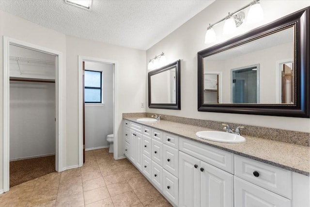 bathroom featuring tile patterned flooring, vanity, a textured ceiling, and toilet