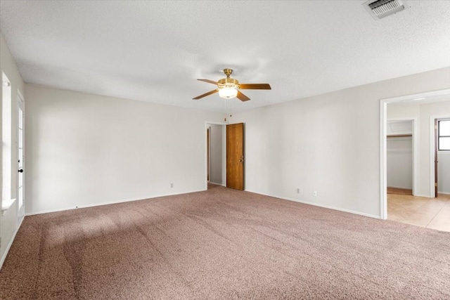 unfurnished room with ceiling fan, light colored carpet, and a textured ceiling