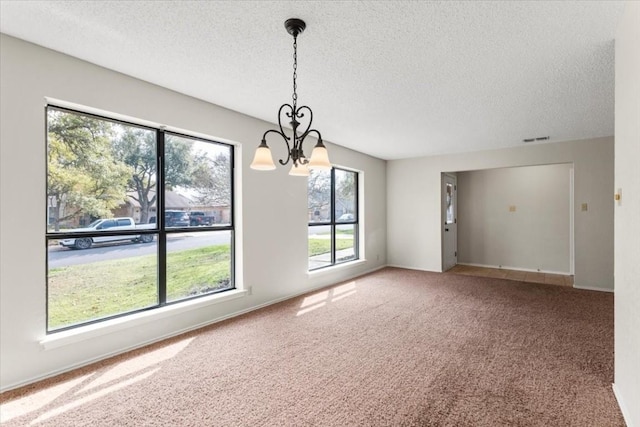 carpeted empty room featuring a textured ceiling and a chandelier