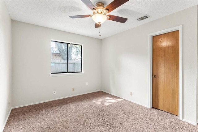 carpeted spare room featuring ceiling fan and a textured ceiling