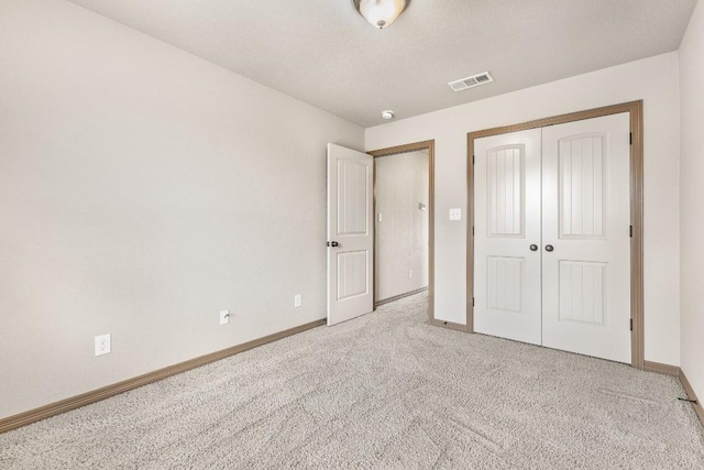 unfurnished bedroom featuring light carpet, a closet, and a textured ceiling