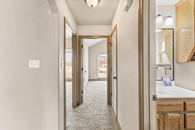 hall with light colored carpet and a textured ceiling