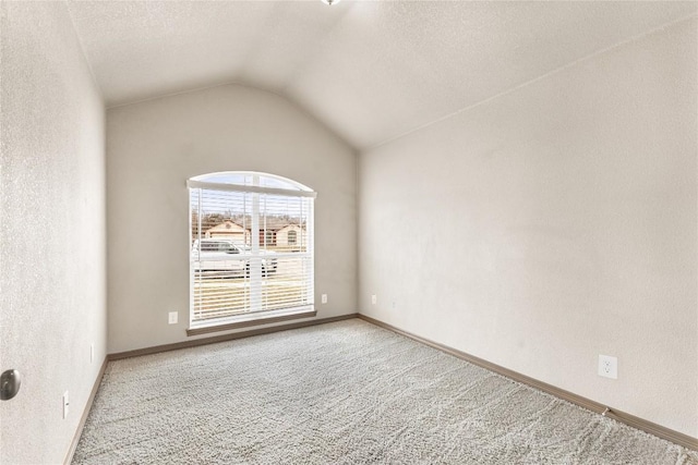 spare room featuring lofted ceiling, light colored carpet, and a textured ceiling