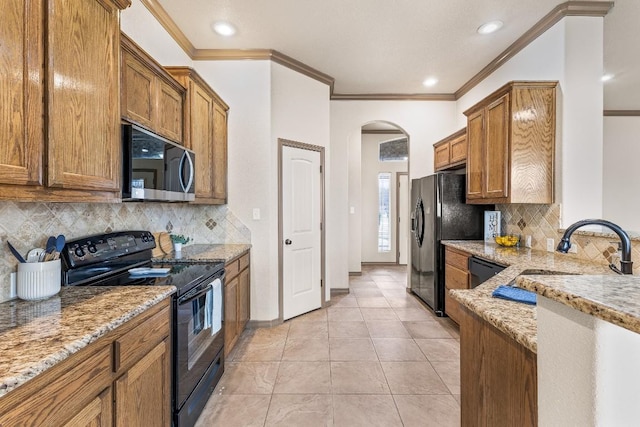 kitchen with light tile patterned flooring, sink, black appliances, crown molding, and light stone countertops