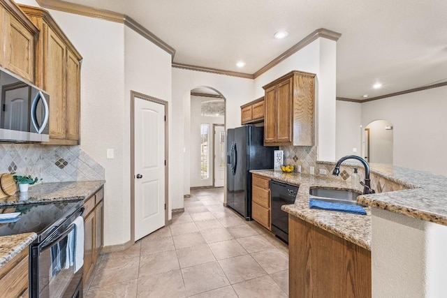 kitchen featuring sink, light tile patterned floors, light stone counters, tasteful backsplash, and black appliances