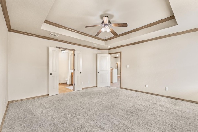 spare room with crown molding, light colored carpet, and a tray ceiling