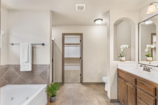 bathroom featuring vanity, toilet, and a tub to relax in