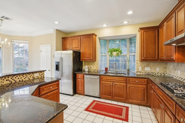 kitchen featuring sink, dark stone countertops, appliances with stainless steel finishes, pendant lighting, and decorative backsplash